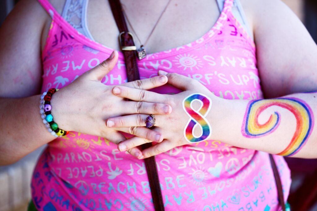 A woman displaying rainbow body paint and holding hands symbolizing diversity and inclusion