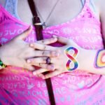 A woman displaying rainbow body paint and holding hands symbolizing diversity and inclusion