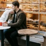 A couple enjoys a relaxing moment with coffee outside a cozy bakery, capturing warmth and affection.