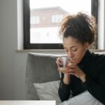 Young woman sipping tea indoors, creating a calming cozy atmosphere. berberine for diabetic nephropathy