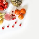 A vibrant flat lay of tropical fruits including bananas, strawberries, and a smoothie on a white background.