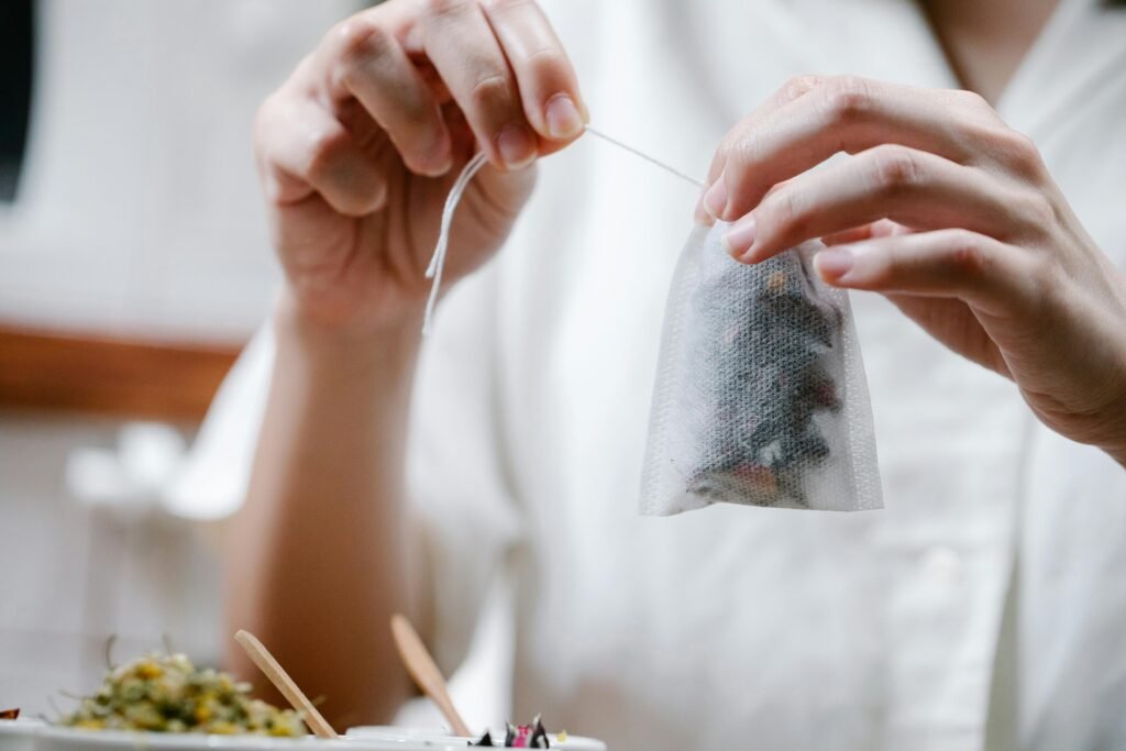 Close-up of hands holding and preparing an herbal tea bag. Perfect for wellness and lifestyle themes.