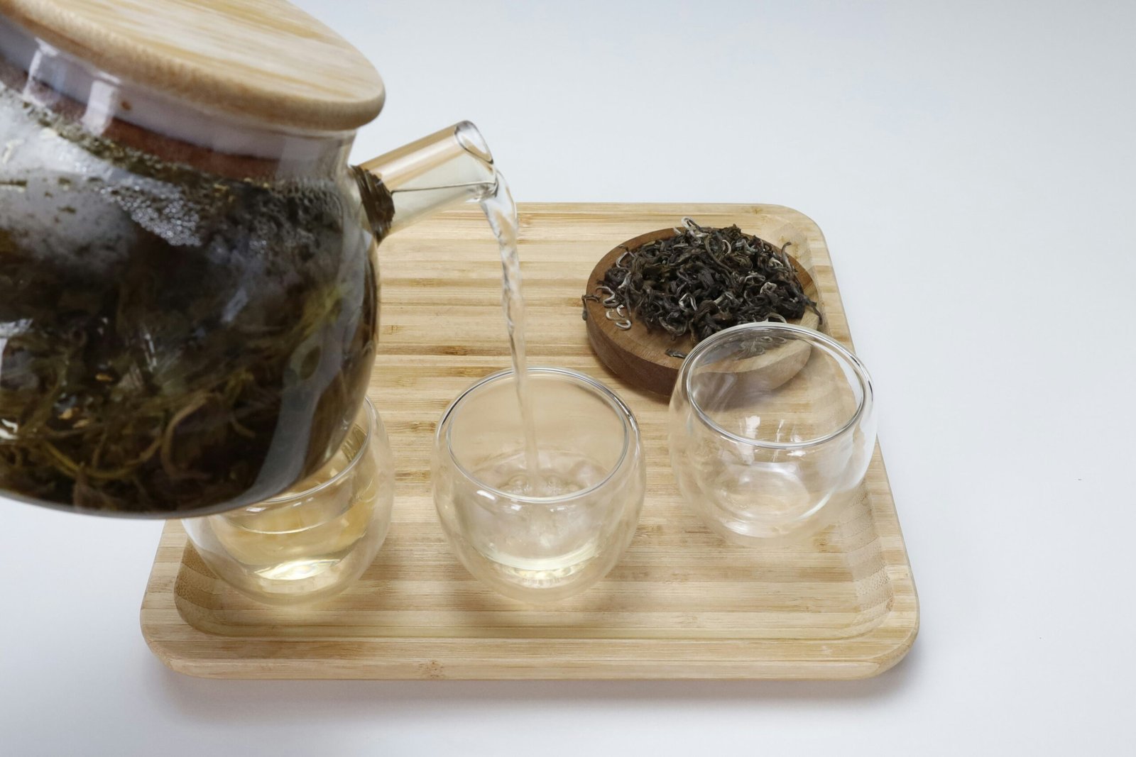 a tea pot pouring tea into two glasses oolong tea for weight loss