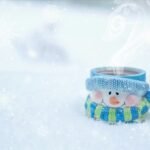 A snowman mug filled with steaming hot cocoa nestled in a snowy winter setting. dibesity berberine tea vs lipton tea